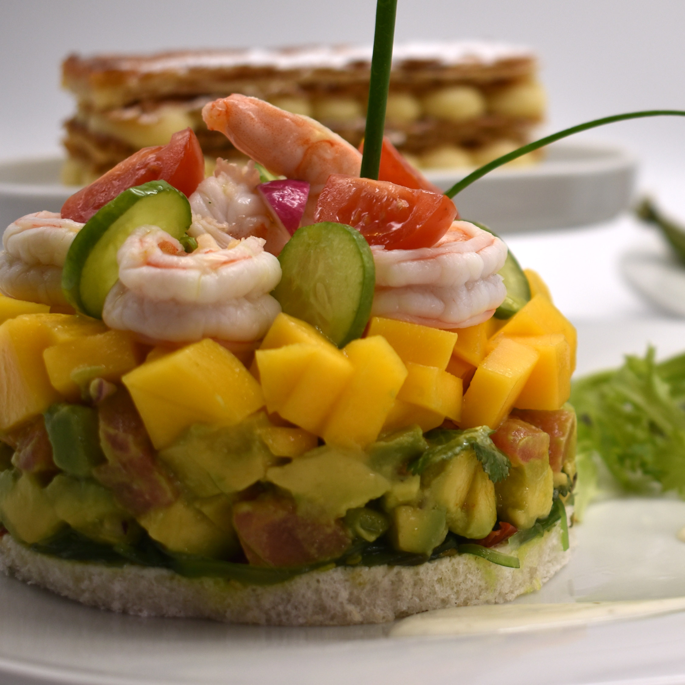 Ensalada de Langostinos Marinados en Timbal sobre Tartar de Aguacate aliñado, Pan Tramezzini , Mango fresco, algas, brotes de lechuga & Vinagreta de Yogur & Mostaza de Dijon con hierbas aromáticas